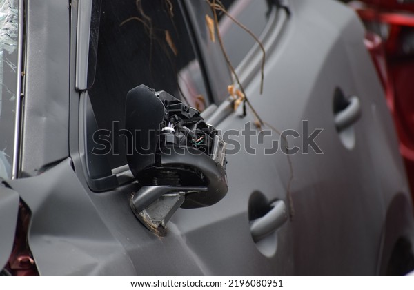 Close up car wing mirror, side view mirror\
broken from accident. Car insurance concept.Damaged car mirror with\
wires sticking out from vandals and hooligans. Repair car after\
accident concept.