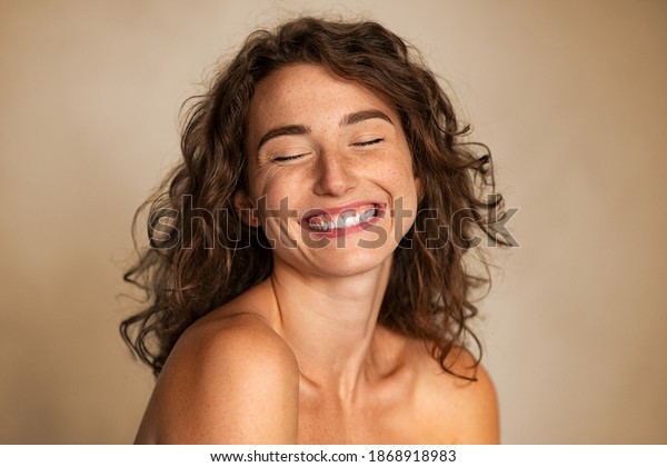 Close up of carefree young woman laughing. Portrait\
of smiling woman with freckles and closed eyes enjoying beauty\
treatment. Beautiful girl laughing isolated on background with copy\
space, skin care.