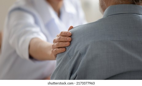 Close up caring doctor touching mature patient shoulder, expressing empathy and support, young woman therapist physician comforting senior aged man at meeting, medical healthcare and help