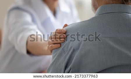 Close up caring doctor touching mature patient shoulder, expressing empathy and support, young woman therapist physician comforting senior aged man at meeting, medical healthcare and help