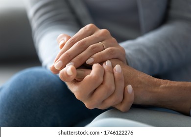 Close up caring grown up daughter holds mother hand provides psychological support, touch arms symbol of asking of forgiveness, heart-to-heart talk with reliable person, empathy and compassion concept