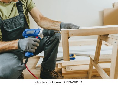 Close up of carpenter drilling a board with a screwdriver. Professional woodworker using tools for work in his workshop. Small business concept. - Powered by Shutterstock