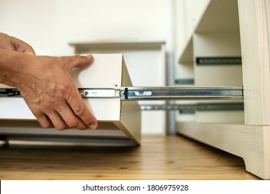 Close up of carpenter hands installing wooden drawer on sliding skids in contemporary cupboard cabinet. - Powered by Shutterstock