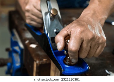 Close up carpenter hands using manual machine working with wood in carpentry workplace