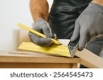 Close up of carpenter measuring wooden board. Professional woodworker using tools for work in his workshop. Small business concept.