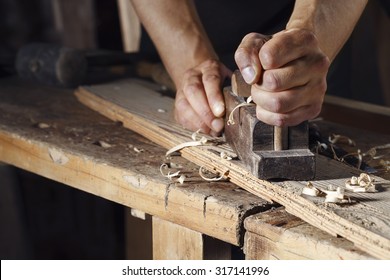 Close up of a carpenter planing a plank of wood with a hand plane