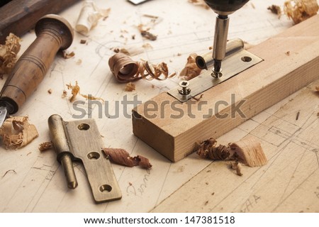 close up  of a carpenter screwed a hinge on a wooden plank