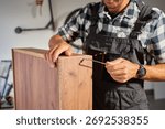 Close up of carpenter using Allen key while assembling wooden furniture in workshop. Man using hex key to tighten screws. Concept of carpentry and furniture making