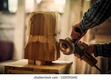 Close up of a  carpenter in work clothes and small buiness owner working in woodwork workshop, processes the board with an angle grinder , on the table is a hammer and many tools  - Powered by Shutterstock