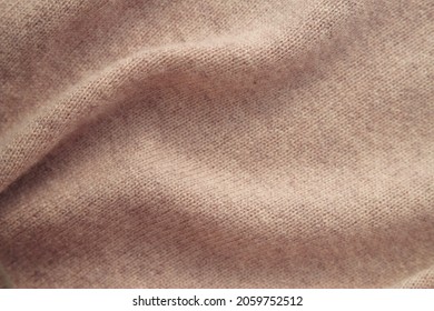 Close up of cashmere fabric with folds. Warm knitted natural background.