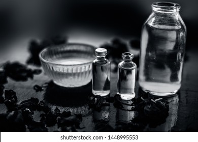 Close Up Of Castor Oil, Tea Tree Oil, And Some Coconut Oil In Bottles On The Wooden Surface Along With Some Raw Honey And Rose Petals Also Present On The Surface.