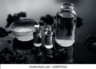 Close Up Of Castor Oil, Tea Tree Oil, And Some Coconut Oil In Bottles On The Wooden Surface Along With Some Raw Honey And Rose Petals Also Present On The Surface.