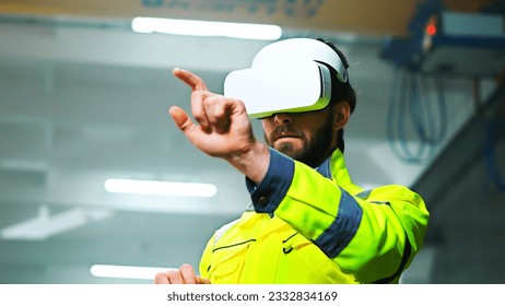 Close up of Caucasian male young engineer in headset and yellow uniform standing in factory and having virtual reality experience. Engineering concept. Indoors. Man in VR goggles moving hands in air. - Powered by Shutterstock