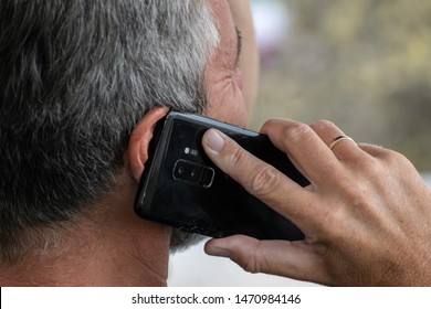 Close Up Of A Caucasian Man Holding A Phone To His Ear On Blurry Background