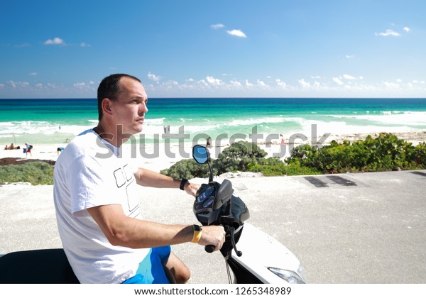 close up of caucasian man on scooter near beach in\
Caribbean sea in Mexico