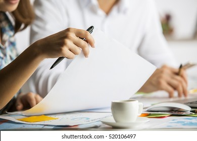 Close up of caucasian man and woman doing paperwork on messy table with coffee cup. Teamwork concept