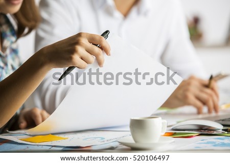 Close up of caucasian man and woman doing paperwork on messy table with coffee cup. Teamwork concept