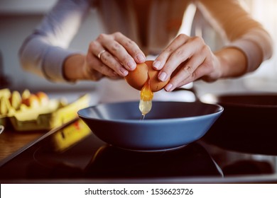 Close Up Of Caucasian Woman Breaking Egg And Making Sunny Side Up Eggs. Domestic Kitchen Interior. Breakfast Preparation.