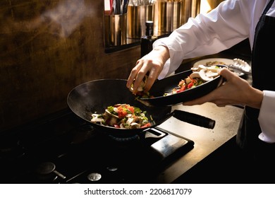 Close up of a Caucasian woman at a cookery class, putting vegetables on a frying pan. Active Seniors enjoying their retirement. - Powered by Shutterstock