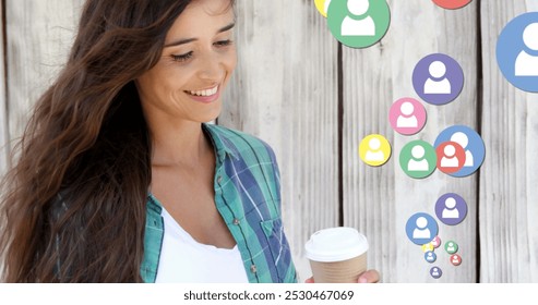 Close up of a Caucasian woman leaning on a wooden wall, checking on her phone while drinking coffee. Follow icons are flying up from her phone. 4k - Powered by Shutterstock