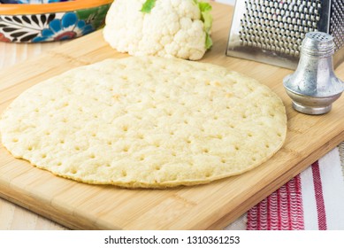 Close Up Of Cauliflower Pizza Crust On A Cutting Board.