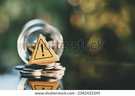 close up caution sign, stack of coin and glass bottle on table, saving and manage money to success business, economic crisis risk and problem concept
