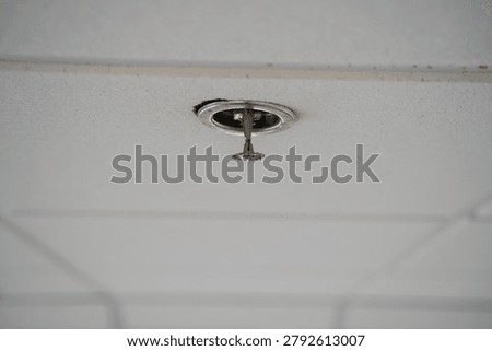 Close up of ceiling mounted fire sprinkler head indoors.