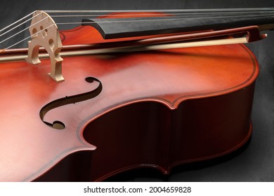 CLOSE UP OF A CELLO LYING ON DARK BACKGROUND. CLASSICAL MUSIC INSTRUMENTS CONCEPT.