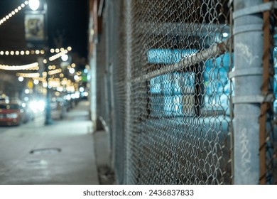 a close up of a chain link fence on a city street at night - Powered by Shutterstock