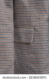 Close up of checked blazer fabric featuring flap pocket and classic houndstooth pattern in beige, blue and brown tones. Elegant tailoring detail suitable for business, smart casual and contemporary fashion collections, ideal for online stores, clothing catalogs and e-commerce listings.