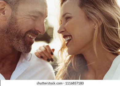 Close up of cheerful man and woman outdoors. Romantic couple together looking at each other and smiling. - Powered by Shutterstock