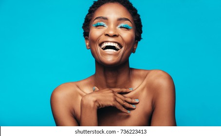 Close Up Of Cheerful Young Woman With Blue Eye Shadow Makeup. Beauty Portrait Of Female Model With Vivid Makeup Laughing On Blue Background.