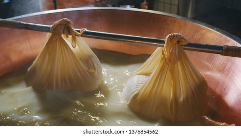 Close up of a cheesemaker is preparing  a form of Parmesan cheese using fresh and biologic milk following the ancient Italian tradition in a dairy factory.