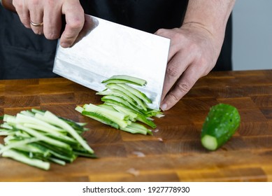 Close Up Of Chef Cook Hands Chopping Vegetables For Traditional Asian Cuisine With Japanese Knife. Professional Sushi Chef Cutting Cucumber For Rolls.