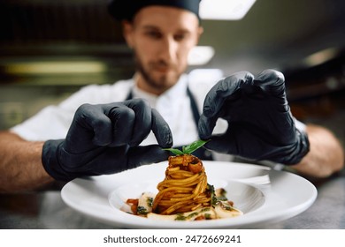 Close up of chef decorating food plate while cooking pasta in the kitchen. - Powered by Shutterstock