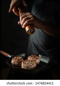 Close up chef hands adding pepper in mill during cooking beef steak on grill pan black background for copy space text restaurant menu, - Shutterstock ID 1476824411