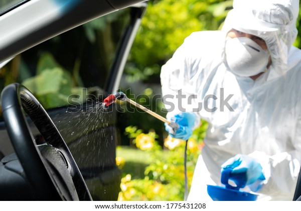 Close up of chemical alcohol spray cleaning\
inside car to disinfect and decontaminate coronavirus covid-19 by\
specialist cleaner wearing personal protective equipment PPE. New\
normal Hygiene concept.