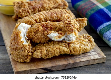 Close Up Of Chicken Fingers On Wooden Cutting Board With Homemade Honey Mustard Dipping Sauce