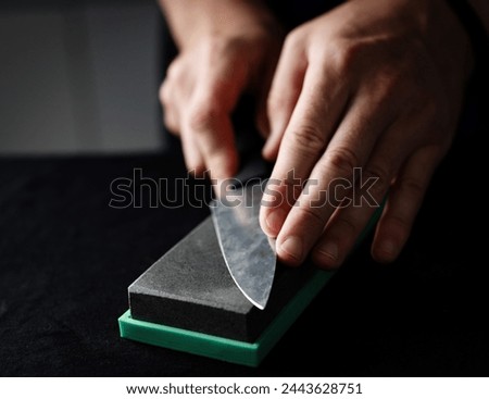 Close Up Of A Chief Hands Sharpening Kitchen Knife With Whetstone