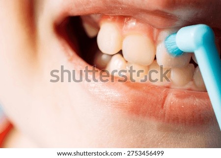 Close up child brushing teeth with a single tuft toothbrush, dental hygiene and oral care