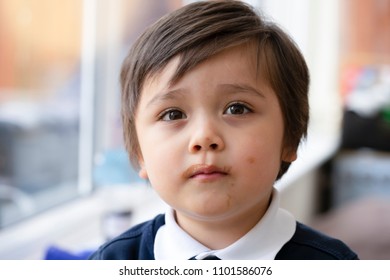 Close up child face with messy mouth from eating chocolate ice cream, Head shot of happy Kid with a dirty face, Little bot with beautiful brown eyes looking at camera with curious or innocent face