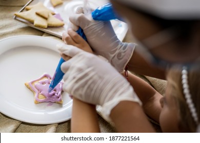 Close Up Of Child Hands Decorating Christmas Biscuits And Gingerbread Cookies In Kitchen Together With Chef. Kids Cooking Class. Merry Christmas And Happy Holidays Concept