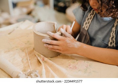 Close up child hands sculpting clay crafts at table in pottery workshop - Powered by Shutterstock