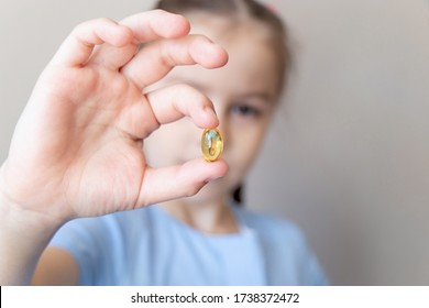 Close Up Child Holding In Hand With Omega 3 Vitamin, Fish Oil Pills. Vitamin D