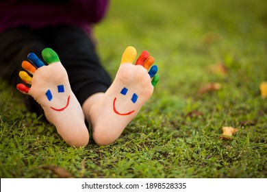 Close up of child human pair of feet painted with smiles outdoor in sunny park with bubble