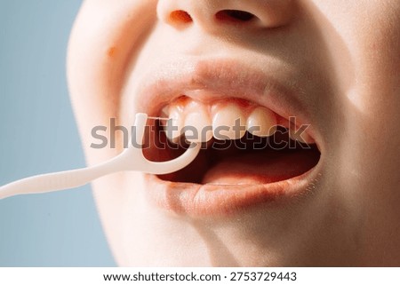 Close up child using a floss pick between teeth, kids dental hygiene routine
