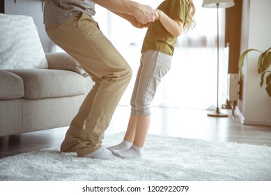 Close Up Of Childish Legs Standing On Male Feet While Dancing. Father And Daughter Having Fun At Home Together 