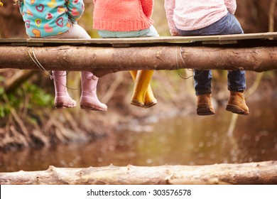 Close Up Of Children's Feet Dangling From Wooden Bridge - Powered by Shutterstock