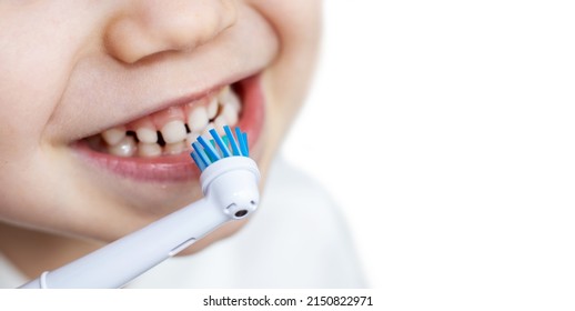 Close Up Of Child's, Little Boy's Mouth Brushing Teeth With Electric Toothbrush. Wide Banner, White Background. Dental Care, Dentist For Kids Concept. Smiling Boy, Diastema. Space For Text.