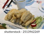 close up of Chinese Cantonese style deep fried bombay duck fish with spicy salt on a white plate